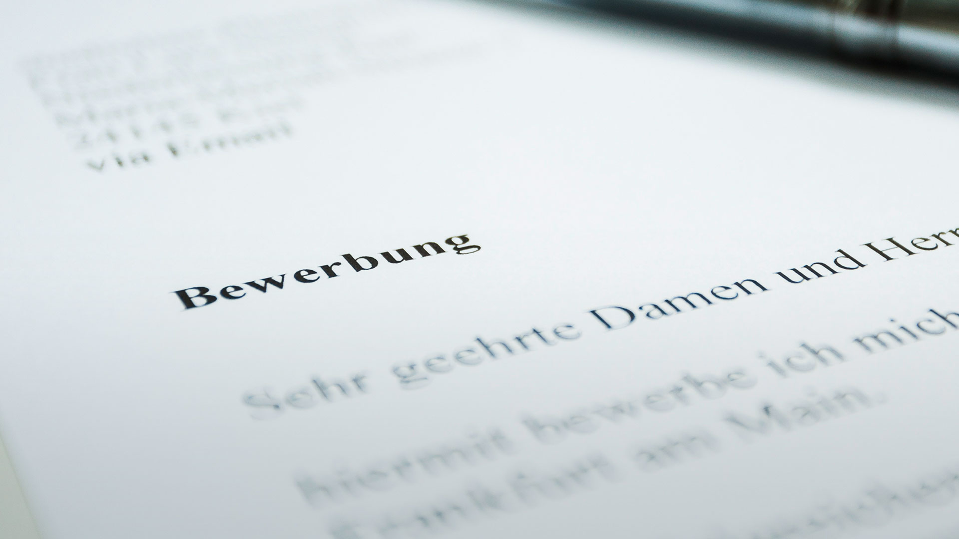 Kreative Bewerbung: das Anschreiben im Zeitungsformat. Zu sehen ist ein Bewerbungsanschreiben mit einem Kugelschreiber darauf.